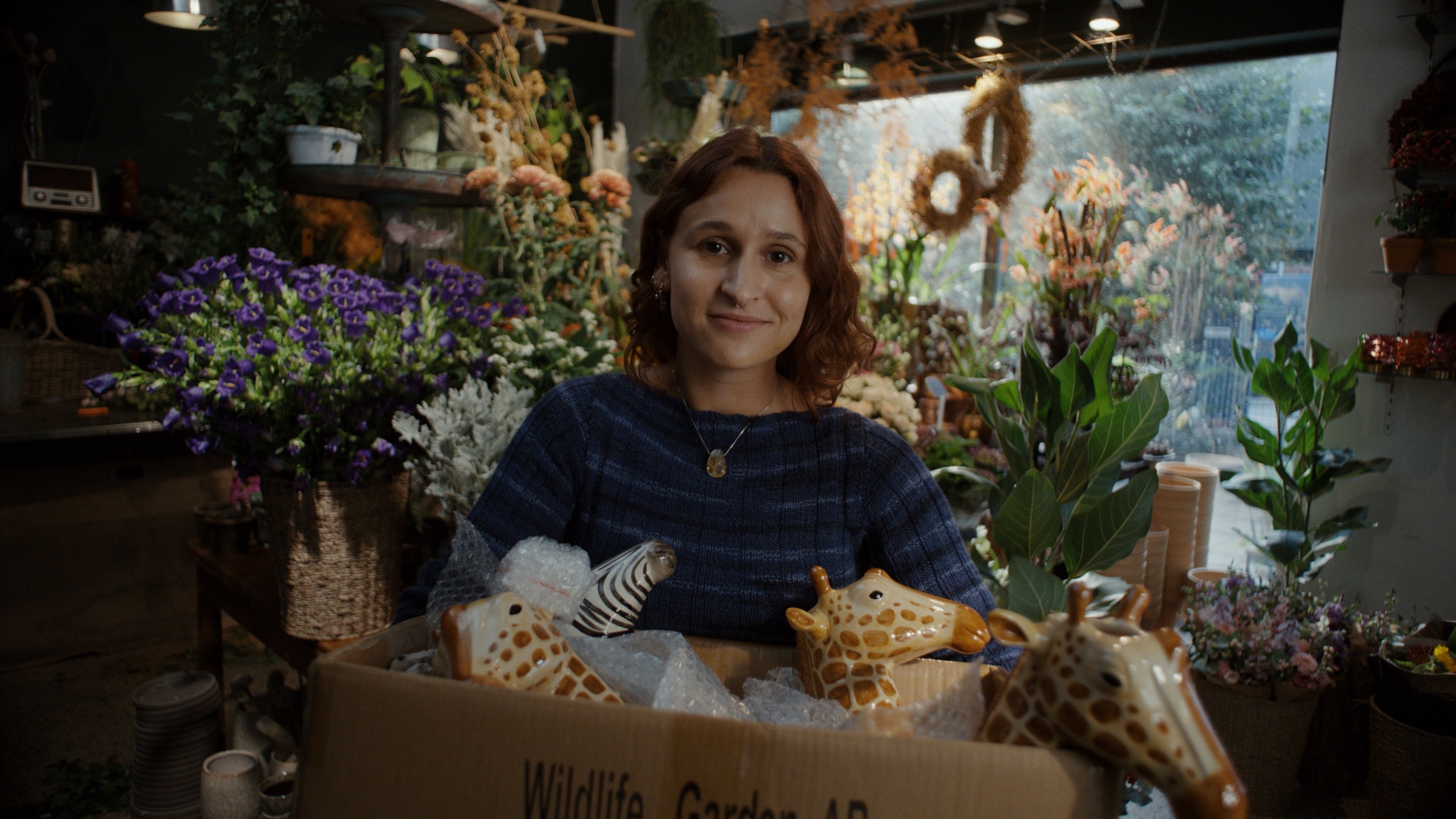 Florist holding a box of ceramic animals in the Dinero Pro campaign